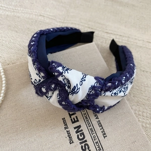Macro shot of blue floral print fabric headband with woven lace trim and knot detail