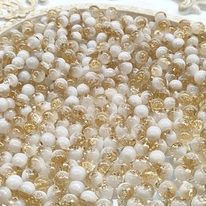 Macro shot of 10mm white and gold crackle glass beads in a white decorative tray