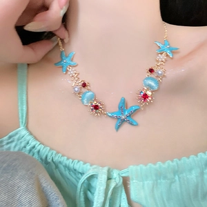 Detailed close-up of a blue starfish pendant necklace with shells on a model's neck