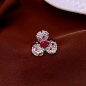 Macro shot of silver clover ring with deep red zircon stone on dark velvet