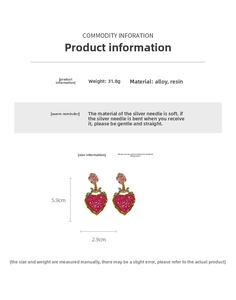 Macro view of vintage heart earrings with red resin and pink rose floral details