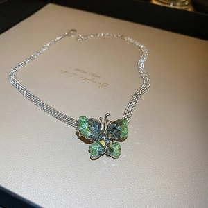 Close-up of green crystal butterfly pendant with a silver multi-strand chain necklace