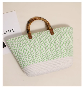 Detail of hand-woven tote bag with natural bamboo handles and green diamond patterns
