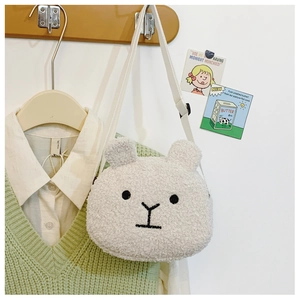 Detailed close-up of a white plush bear head shoulder bag hanging on a wooden hook