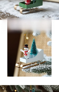 Detail of Santa and snowman on iron sleigh ornaments hanging on a Christmas tree