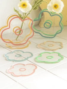 Close-up of colorful flower-shaped acrylic coasters and wave vases on white tile