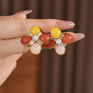 Détail de boucles d'oreilles vintage avec pétales en résine colorée et perle centrale