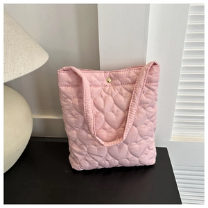 Detail of pink quilted tote bag showing heart stitching pattern and gold button closure