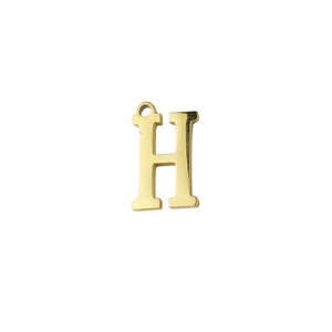 Macro shot of a golden letter H pendant charm with a polished mirror finish for DIY jewelry