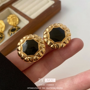 Detailed macro shot of vintage gold flower stud earrings with black enamel inlay