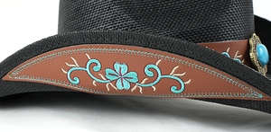 Dettaglio cappello cowboy nero intrecciato con cinturino in pelle e gemma turchese