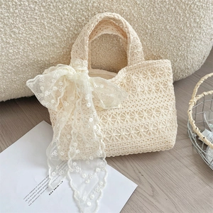 Detail of cream crochet tote bag featuring intricate floral lace ribbon and woven texture