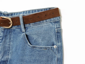 Detail of high-waist blue denim culottes with brown suede belt and stitching texture