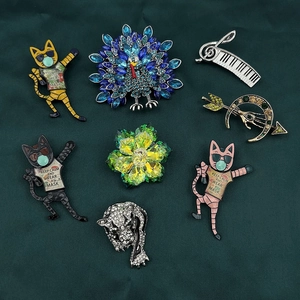 Detailed collection of crystal brooches including cartoon cats, peacocks and floral designs