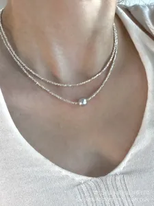 Close-up of a double-layered 925 silver necklace with a gray pearl on a model's neck