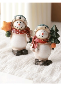 Close-up of cute resin snowman figurines with festive scarves and mini Christmas trees
