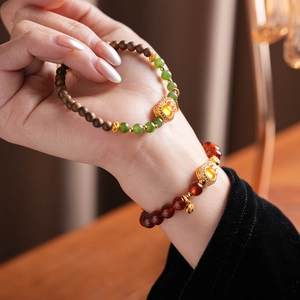 Detailed view of layered garnet beads and jade gourd charm on a minimalist bracelet