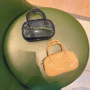 Top view of mini PVC jelly bags in black and beige on a green leather stool