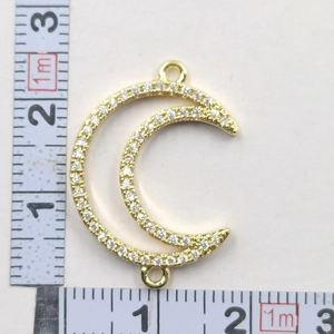 Detailed macro view showing a gold crescent moon pendant with rhinestones and size measurements