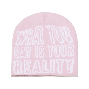 Detailed knit texture of pink beanie with What You Say Is Your Reality slogan