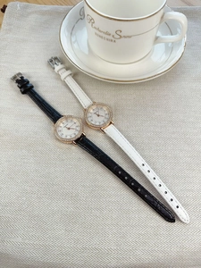 Detail of luxury crystal bezel watches with black and white leather straps on a cafe table