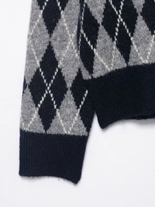Detail of ribbed cuffs and hem on argyle knit sweater in navy blue and grey