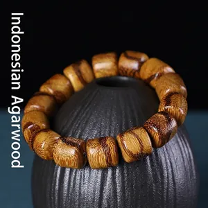 Indonesian agarwood bucket bead bracelet with natural dark grain on a ceramic jar
