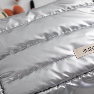 Close-up of puffy silver quilted cosmetic bag showing metallic texture and brand label