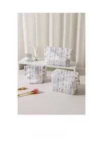 Close-up of three purple floral cosmetic bags in various sizes with MAR BAG woven labels
