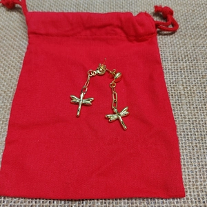 Golden dragonfly long drop earrings displayed on a red gift pouch for women
