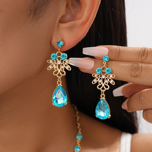 Close-up of elegant gold earrings with blue drop-shaped stones and intricate filigree detail