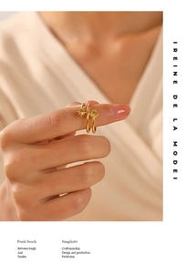 Detailed close-up of golden double-layer ring with star and sunburst motifs held in fingers