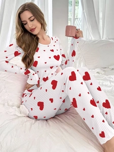 Detail of white ribbed pajamas featuring red heart prints in a cozy bedroom setting