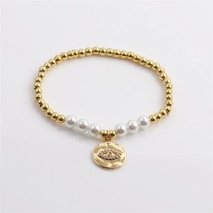 Bracciale elastico dorato con perle bianche e ciondolo occhio del male con zirconi