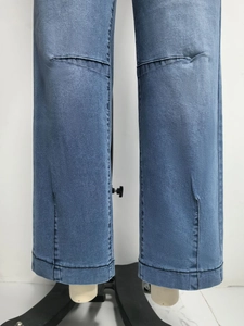 Détail de l'ourlet fendu et des surpiqûres contrastées sur un jean droit bleu foncé