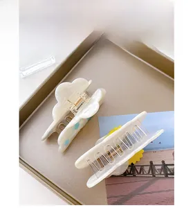 Cloud pattern hair claw and sunflower shark clip resting on a leather tray