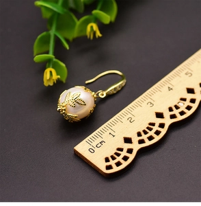Baroque pearl earring detail with gold leaf design and measuring ruler for size view