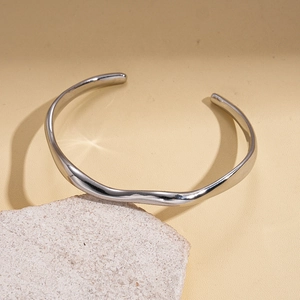 Detailed view of silver minimalist wavy open cuff bracelet on stone display stand