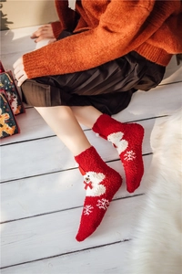 Detail of red coral fleece Christmas sock with white bear pattern and plush pom-poms