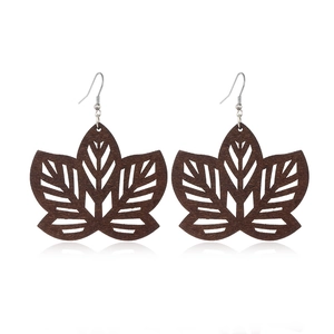 Macro detail of dark brown leaf-shaped hollow wood earrings with geometric cutouts