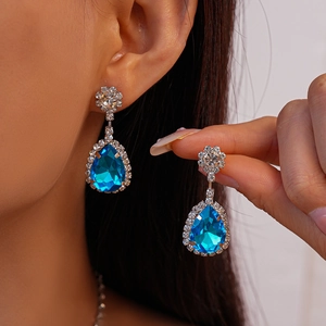 Gros plan sur d'élégantes boucles d'oreilles fleur argentées avec cristaux bleus en poire