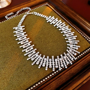 Detail shot of a silver rhinestone necklace on a green velvet vintage jewelry tray
