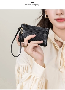 Detail of black pebbled leather mini coin purse with double gold zippers and wrist strap
