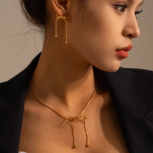 Elegant gold bow necklace and tassel earrings set worn by model for luxury look