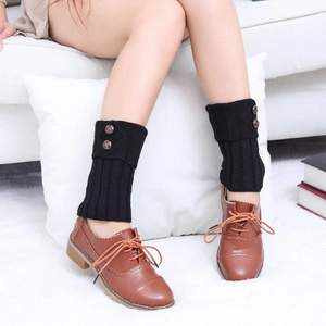 Close-up of black cable-knit leg warmers featuring two brown buttons and retro design