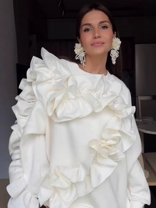 Elegante felpa bianca con volant e orecchini a fiore con perle per un look invernale chic