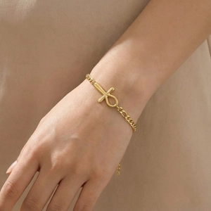 Elegant gold Ankh cross bracelet on female wrist with minimalist satin metal finish