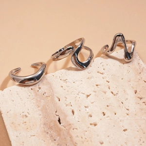 Silbernes dreiteiliges Set unregelmäßiger Metallringe auf einem Natursteinsockel