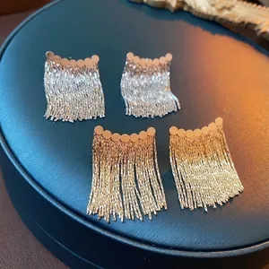 Elegant gold and silver round metal tassel chain earrings on a blue display stand