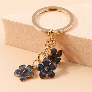 Detail of vintage gold keychain with three black enamel flowers and petal textures